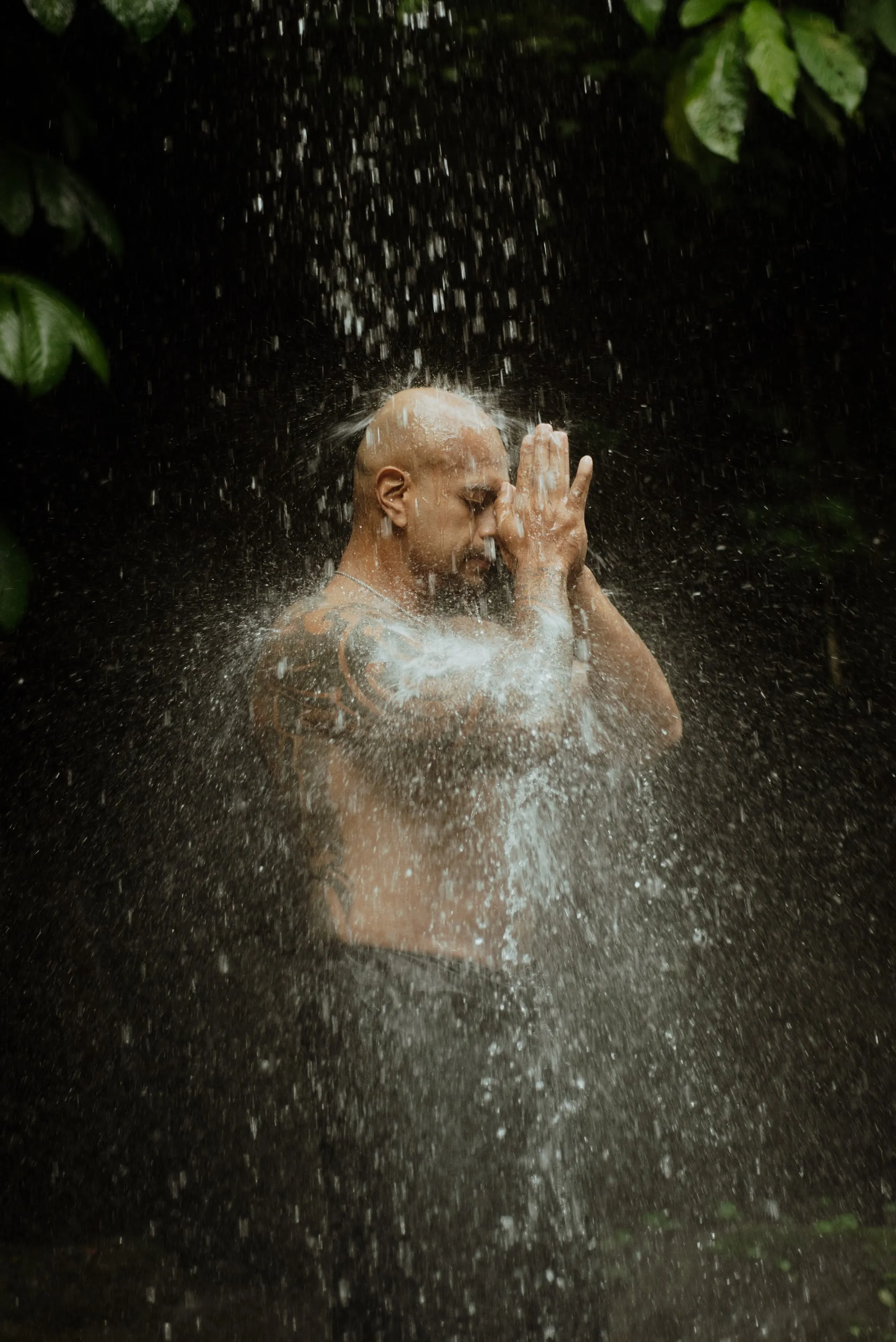 Andy standing under falling water, hands at his face, eyes closed