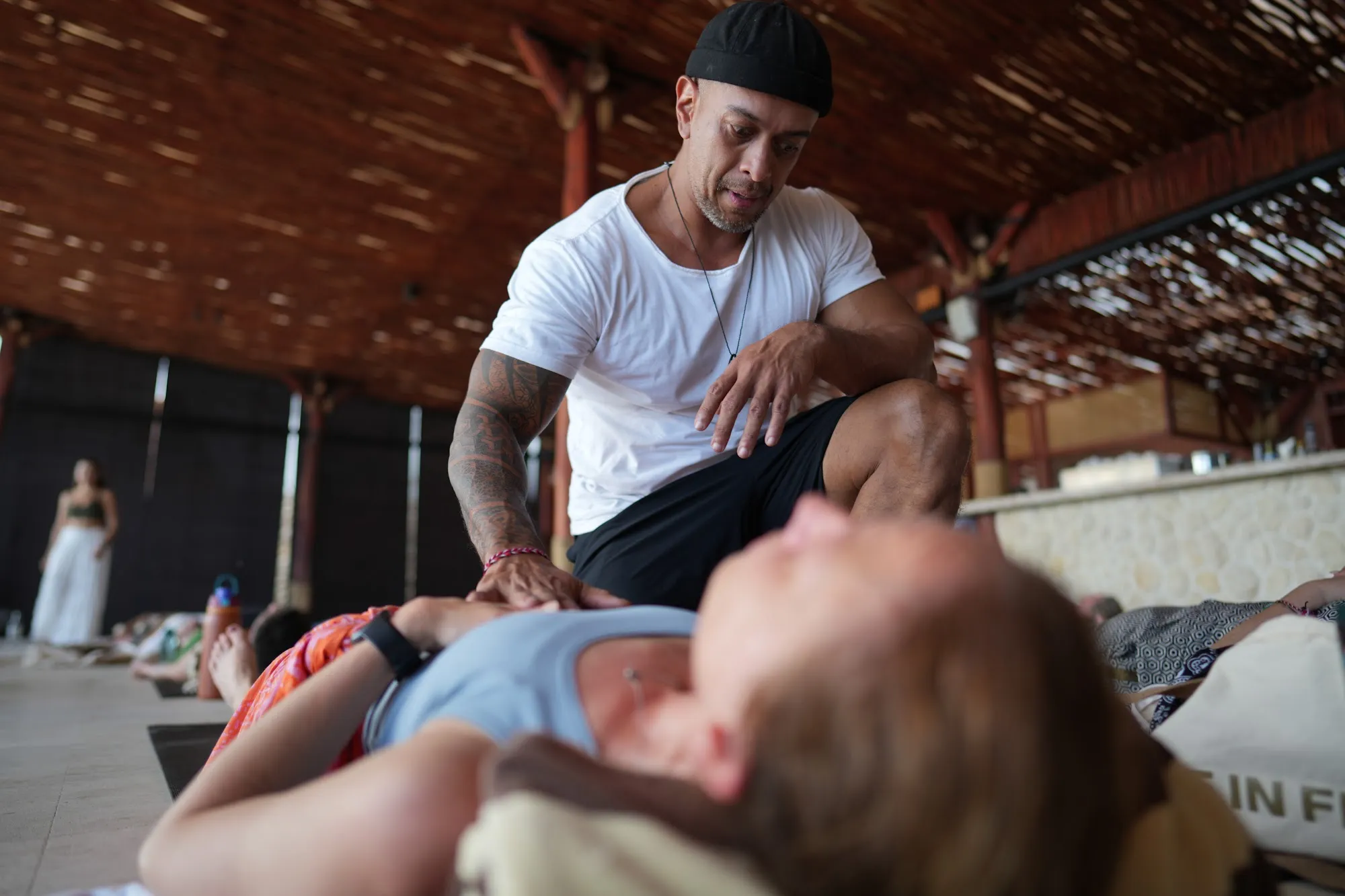 Andy kneeling beside a participant on the mat, guiding her breath