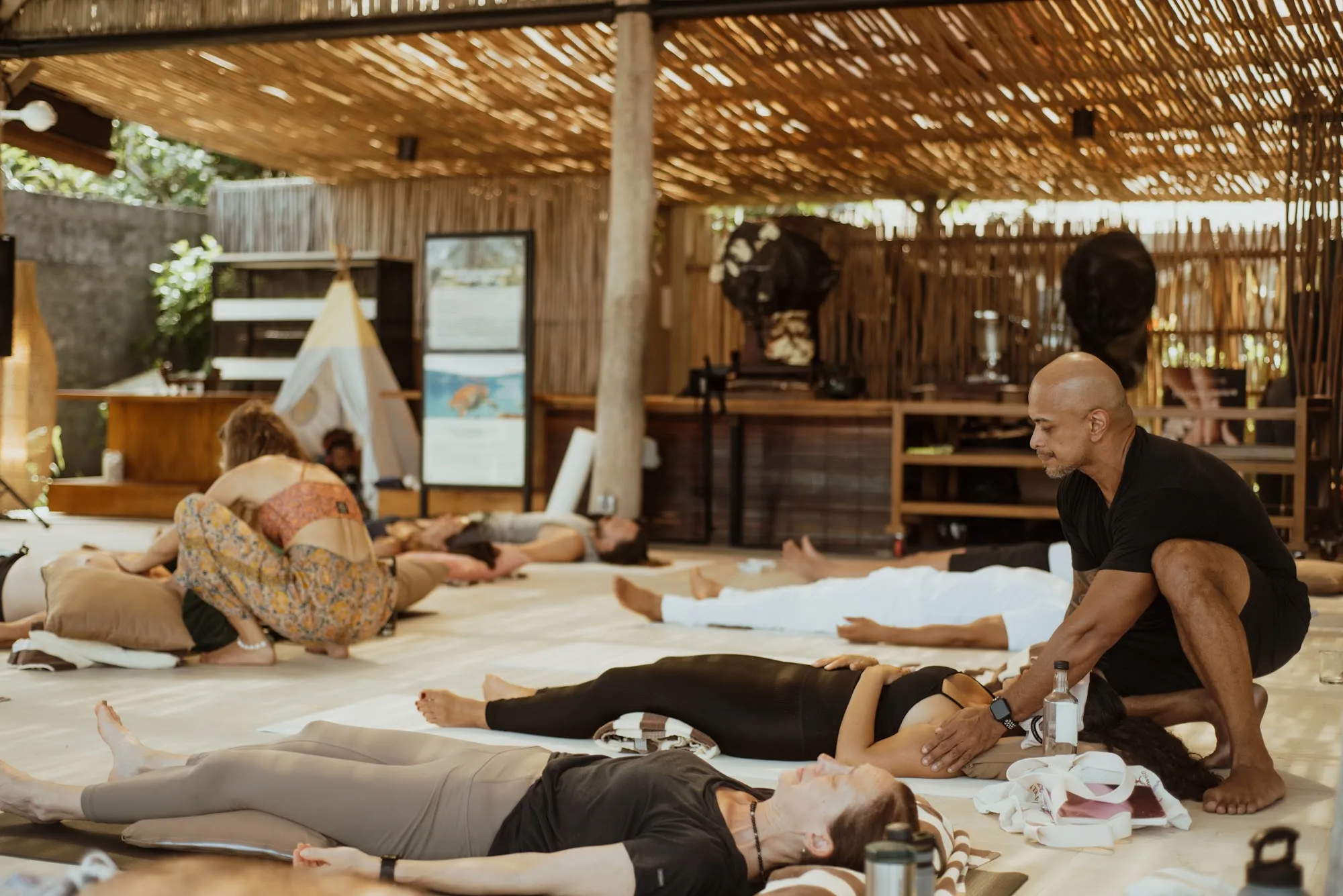 The open bamboo practice hall, participants resting on mats while Andy works with one of them