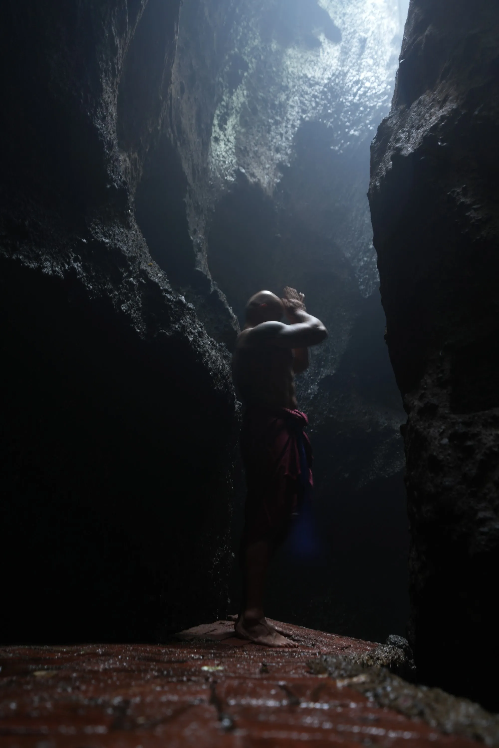 A single figure standing still in a beam of light inside a cave