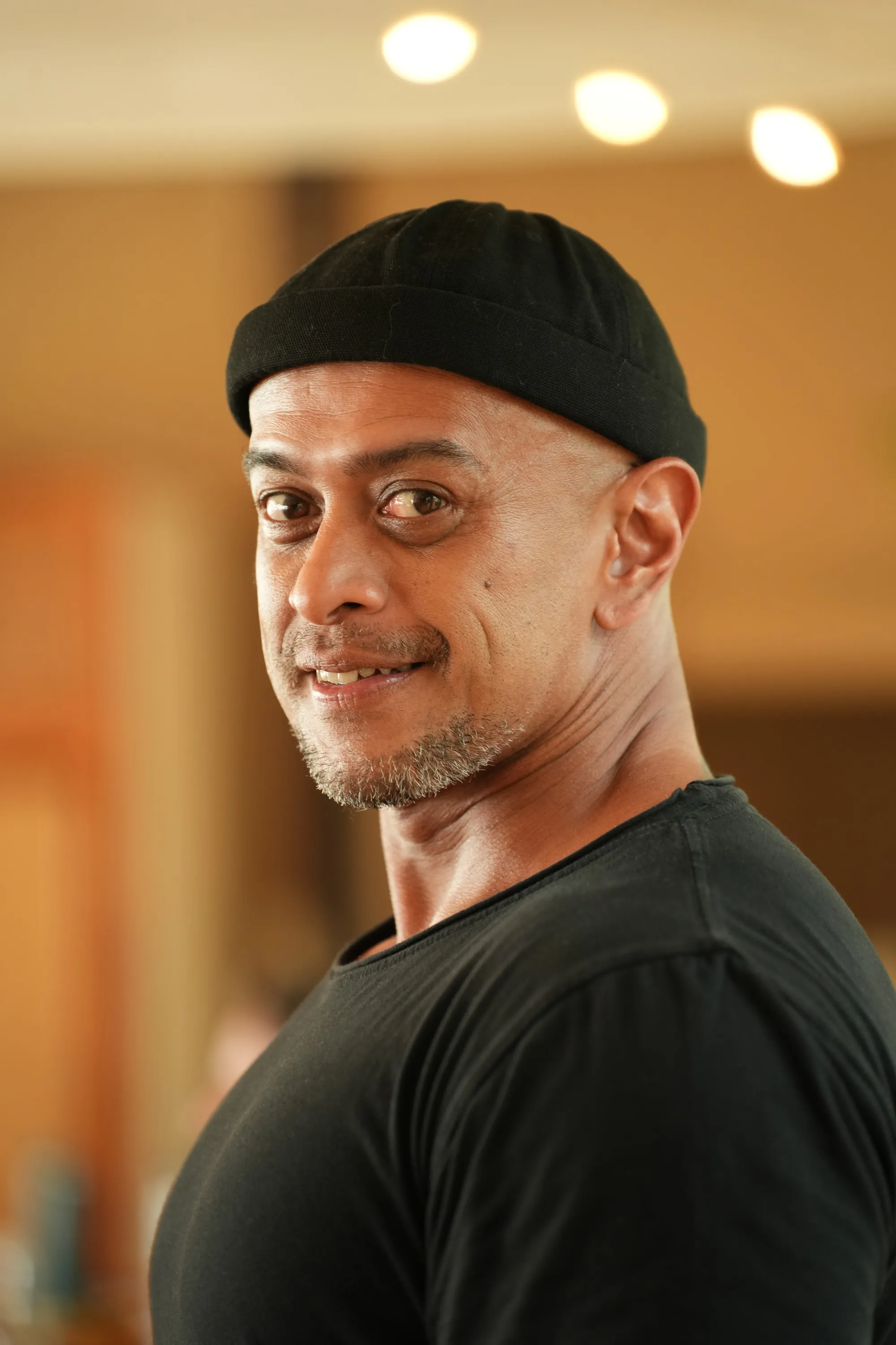 Portrait of Andy in a black beanie, smiling at the camera